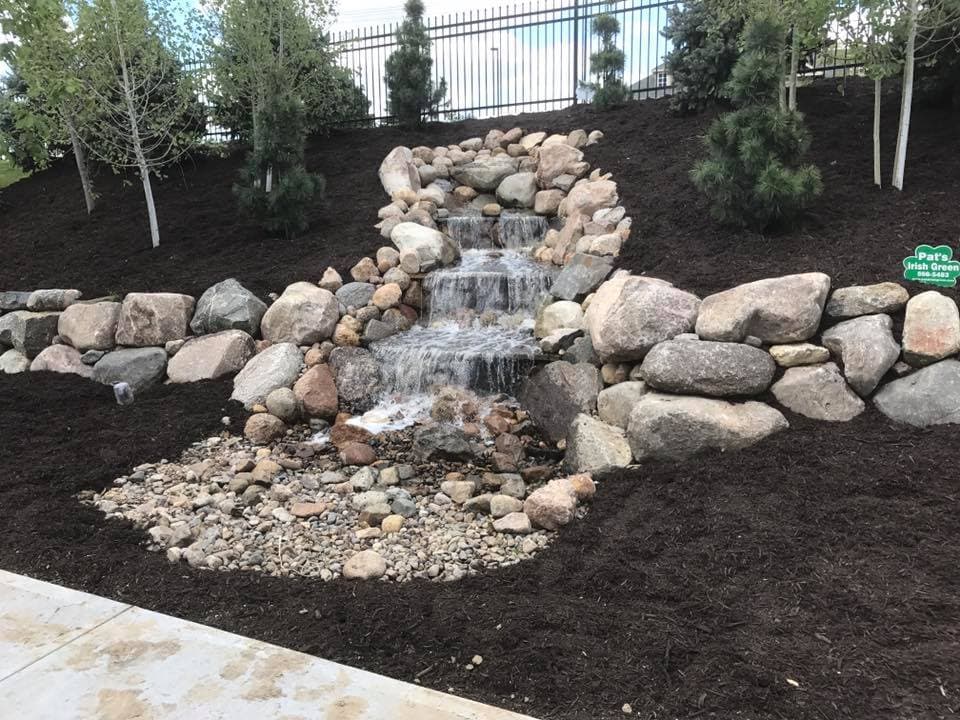 Custom stone water feature and waterfall hardscape installed by Pat's Irish Green