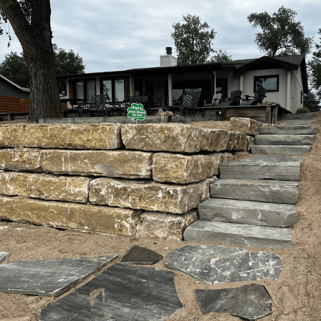 Stone seawall and paver steps installed by Pat's Irish Green at an Omaha lakefront property